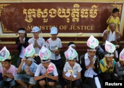 FILE - Children of Boeung Kak women protesters wear portraits of their mothers around their foreheads as they pray at a protest in front of the Ministry of Justice in Phnom Penh.