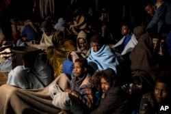 FILE - In this photo taken Feb. 18, 2018, refugees and migrants sit on the deck of a rescue ship after being rescued by aid workers of the Spanish NGO Proactiva.