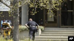 An Oakland police officer approaches the entrance to Oikos University in Oakland, Calif., Monday, April 2, 2012.