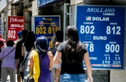 People walk past a bureau de exchange were currency exchange is displayed in Santiago, Chile, Dec. 2, 2019.