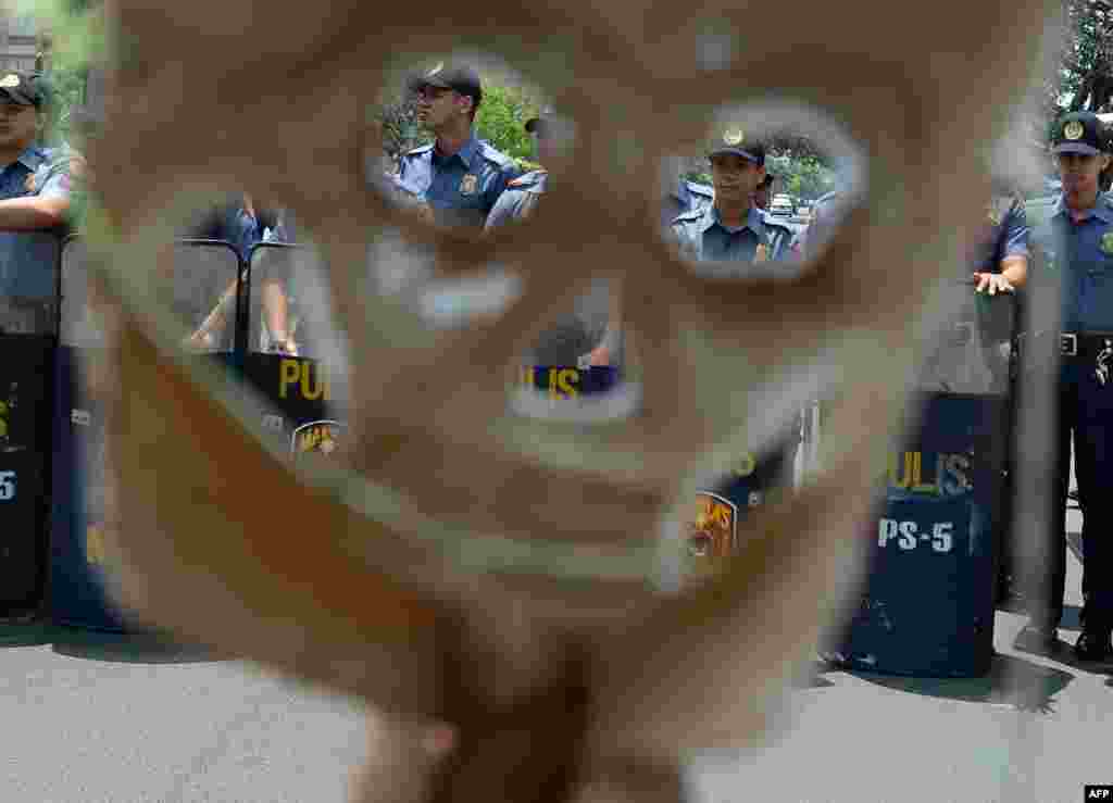 Policemen blocking protesters are seen through the mask of a protester during a protest against a greater US military presence, near the US embassy in Manila, Phillipines ahead of US President Barack Obama&#39;s visit in April.