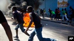 Protesters run past a barricade to a nearby depot that was being looted, during a protest demanding the resignation of President Jovenel Moise in Port-au-Prince, Haiti, Feb. 11, 2019. 