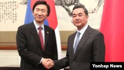 왕이 중국 외교부장(오른쪽)이 지난해 4월 베이징에서 윤병세 한국 외교장관의 회담에 앞서 악수를 나누고 있다. (자료사진)