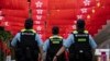 FILE - Police walk past Chinese and Hong Kong flags in Hong Kong, July 1, 2024. As economic pressures constrain budgets, Chinese police have been using flexible legal codes and financial punishments to fill government coffers, analysts say.