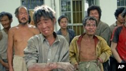 Workers forced to work as slaves - given only bread, water and no pay - stand at a police station after they were rescued from a brickworks run by the son of a local Communist Party official, in Hongdong County in Linfen, north China's Shanxi province, M