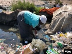 A woman is seen washing clothes in the Mukuvisi River in Harare, Zimbabwe, Sept. 11, 2018, as water shortages persist, what experts say is fueling the spread of cholera. (C. Mavhunga/VOA)
