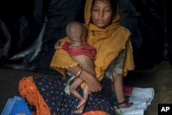 A Rohingya Muslim woman, who crossed over from Myanmar into Bangladesh, holds her 10-month-old son inside her shelter in Thaingkhali refugee camp, Bangladesh, Saturday, Oct. 21, 2017.