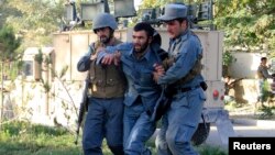 Afghan policemen help an injured comrade at the site of a suicide bomb attack in Ghazni Province, September 4, 2014.