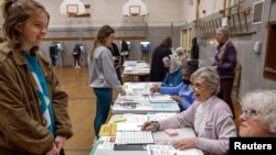 FILE - Election workers assist voters at Maryland Avenue Montessori School during Wisconsin's Supreme Court election in Milwaukee, April 4, 2023. 