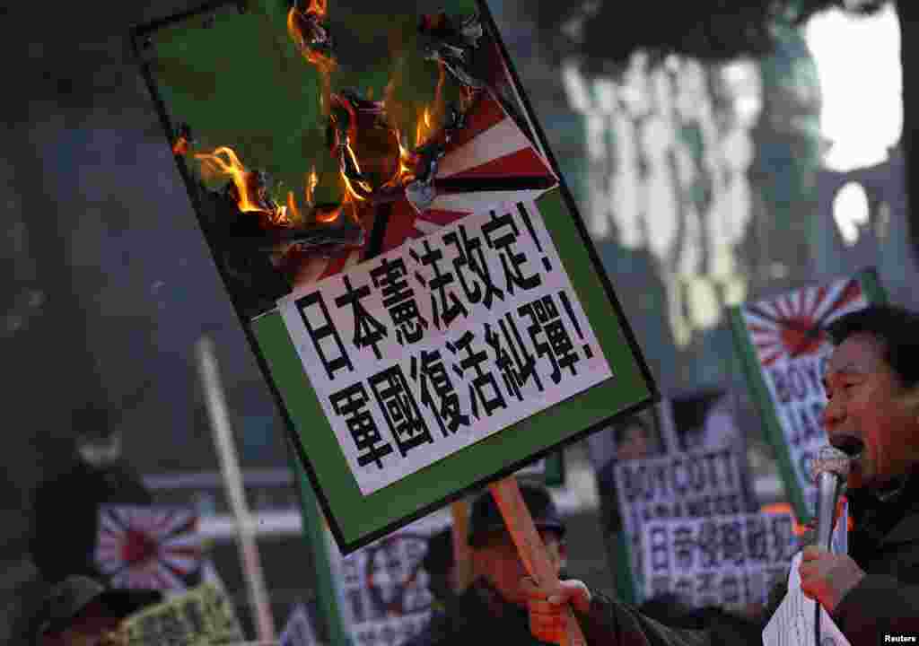 일본 아베 총리의 신사참배에 항의하는 반일 시위가 고조되는 가운데 27일 서울 일본대사관 앞시위대가 욱일승천기를 태우고 있다.