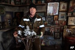 Viktor Mikhalev shows roses transformed from weapons and ammunition into flowers of war standing in a workshop in his house in Donetsk. (AP Photo/Alexei Alexandrov)