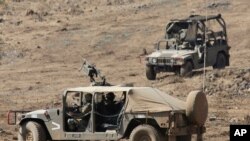 FILE - Israeli soldiers drive military vehicles during an exercise in the Israeli controlled Golan Heights near the border with Syria, August 4, 2020. 