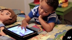 In this Oct. 21, 2011 file photo, Frankie Thevenot, 3, plays with an iPad in his bedroom at his home in Metairie, La. WHO announced that children under five years old should not spend more than one hour a day watching such devices.