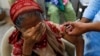 FILE - Basanti, 71, reacts as she receives a dose of the coronavirus disease (COVID-19) vaccine at a vaccination center in Karachi, Pakistan, June 9, 2021.