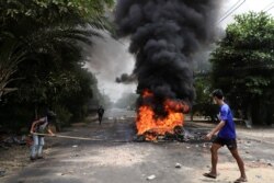Seorang pengunjuk rasa anti-kudeta berjalan melewati ban yang terbakar, setelah para aktivis melancarkan "pemogokan sampah" terhadap aturan militer, di Yangon, Myanmar 30 Maret 2021. (REUTERS / Stringer)