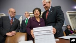 Rep. Pete Sessions, R-Texas, right, welcomes Rep. Nita Lowey, D-N.Y., and Rep. James P. McGovern, D-Mass., far left, as they gather at the Capitol around a printout of the $1.1 trillion spending bill to fund the government for fiscal 2016, Dec. 16, 2015.