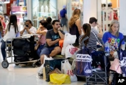 People take a break while shopping on Black Friday at Dolphin Mall, Nov. 23, 2018, in Miami.