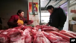 FILE - A customer looks at meat at a shop in Shanghai. 