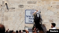 Rai mmoja wa Palestina akiondoa alama kwenye ukuta katika eneo la msikiti wa Al-Aqsa Mosque, kufuatia mapigano na askari wa Israeli huko Old City Jerusalem.