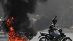 A man flashes the three-finger salute as he passes burning tires during a protest against the military coup, in Mandalay, Myanmar April 1, 2021. REUTERS/Stringer