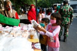 Anak-anak mengenakan masker menerima bantuan makanan gratis di tengah pandemi virus corona di Jakarta. (foto: ilustrasi)