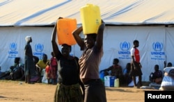 FILE - Women who fled fighting in South Sudan carry water in plastic container on arrival at Bidi Bidi refugee’s resettlement camp near the border with South Sudan, in Yumbe district, northern Uganda, Dec. 7, 2016.