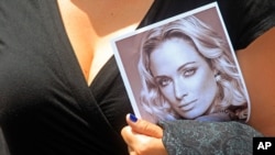 A woman holds a photo of Reeva Steenkamp as she leaves her funeral in South Africa, February 19, 2013.