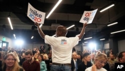 FILE - A campaign worker hands out signs at a campaign event for Democratic presidential candidate and former New York City Mayor Michael Bloomberg, in Providence, Rhode Island, Feb. 5, 2020.
