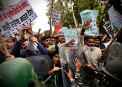 FILE - Security officers push back people shouting slogans during a protest held to show support to farmers who have been on a monthslong protest, in New Delhi, India, Feb. 3, 2021.