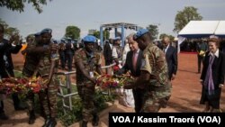 Le secrétaire général de l'ONU, Antonio Guterres, au milieu de deux casques bleus, déposent une gerbe de fleurs en mémoire des soldats onusiens décédés au Mali, 30 mai 2018. (VOA/Kassim Traoré)