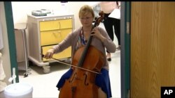 FILE - In this image taken from video, cellist Martha Vance plays for a patient at Medstar Georgetown University Hospital in Washington, Oct. 11, 2017.