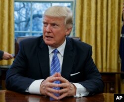 President Donald Trump sits at his desk in the Oval Office of the White House in Washington.