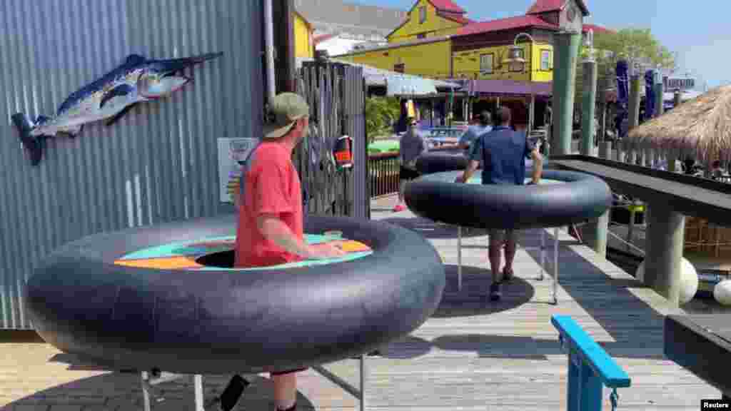 Employees roll out inflatable inner tubes on wheels, to be used as social distancing tables amid the coronavirus disease (COVID-19) outbreak, at Fish Tales restaurant and bar in Ocean City, Maryland, U.S. May 16, 2020 in this still image taken from social