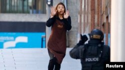 A hostage runs toward a police officer outside Lindt cafe, where other hostages are being held, in Martin Place in central Sydney, Australia, Dec. 15, 2014. 