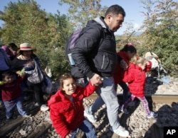 Migrants walk along the railway tracks after crossing from Greece to Macedonia, at the border line between the two countries, near southern Macedonia's town of Gevgelija, Aug. 23, 2015.