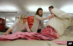 Election workers Heidi McGettigan, left, Margaret Wohlford, center, and David Jensen, unload a bag of ballots brought in a from a polling precinct to the Sacramento County Registrar of Voters office in Sacramento, Calif., June 5, 2018.