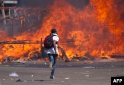 FILE - Zimbabwe's opposition supporters set up a burning barricade as they clash with police during a protest for electoral reforms, Aug. 26, 2016 in Harare, Zimbabwe.