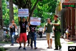 ប៉ូលិសម្នាក់​ព្យាយាម​ហាម​ឃាត់​ក្រុម​បាតករដែល​បាន​លើ​បដាប្រឆាំង​នឹង​ជំហរ​របស់​ចិន​ជុំវិញ​បញ្ហា​សមុទ្រ​ចិន​ខាង​ត្បូង នៅទីក្រុងហាណូ កាលពីថ្ងៃទី១៧ ខែកក្កដា ឆ្នាំ២០១៦។