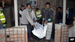Men remove the body of a suspected suicide bomber after an explosion was touched off at a mosque of a minority Ahmadiya Muslim sect, in Bagmara, Rajsahi district, Bangladesh, Dec. 25, 2015.