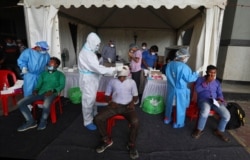 FILE - Migrant laborers returning to the city for work undergo COVID-19 tests in New Delhi, India, Aug. 18, 2020.