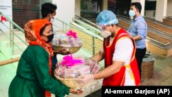 Members of Bidyanondo Foundation distribute packages to people receiving them on behalf of COVID-19 patients in Dhaka, Bangladesh, June 6, 2020. (AP Photo/Al-emrun Garjon)