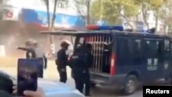 ภาพของจนท.ความมั่นคงจีนที่ยืนใกล้ ๆ กับรถตำรวจคันหนึ่งหลังมีกระสุนปืนใหญ่ตกเข้ามาในเมืองหนานซาน มณฑลยูนนาน