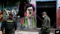 Polisi berdiri di depan gambar mural gembong narkoba Pablo Escobar, di kawasan El Bronx, di pusat kota Bogota, Kolombia, 30 Mei 2016.
