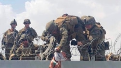 This image from video provided by Omar Haidari and taken, Aug. 19, 2021, shows a baby being lifted across a wall at the Kabul airport in Afghanistan by US soldiers.
