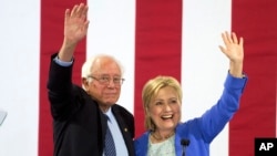 លោក​ Bernie Sanders និង​លោក​ស្រី Hillary Clinton លើក​ដៃ​ទៅ​កាន់​អ្នក​គាំទ្រ​នៅ​ក្នុង​ការ​ឃោសនា​បោះ​ឆ្នោត​នៅ​ក្រុង​ Portsmouth ក្នុងរដ្ឋ​ New Hampshire កាល​ពី​ថ្ងៃ​ទី​១២ ខែ​កក្កដា។