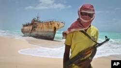FILE - In this 2012 photo, a Somali pirate stands near a Taiwanese fishing vessel washed ashore after the pirates were paid a ransom and the crew were released.
