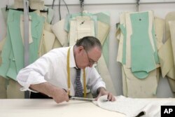 FILE - An employee cuts fabric at a factory in New York's garment district.