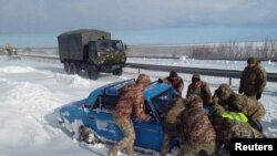 资料照片：乌克兰军人在敖德萨地区帮助一辆陷在大雪中的汽车脱险。(2023年11月28日）