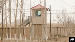 FILE - A security person watches from a guard tower around a detention facility in Yarkent County in northwestern China's Xinjiang Uyghur Autonomous Region, March 21, 2021. China's treatment of Uyghurs has been condemned by human rights organizations as crimes against humanity.