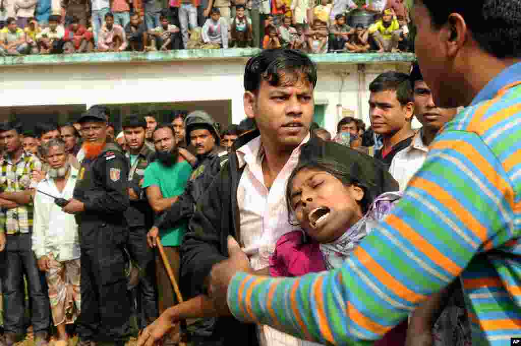 People console a woman whose relative was killed in a fire at a garment factory outside Dhaka, Bangladesh, November 25, 2012.
